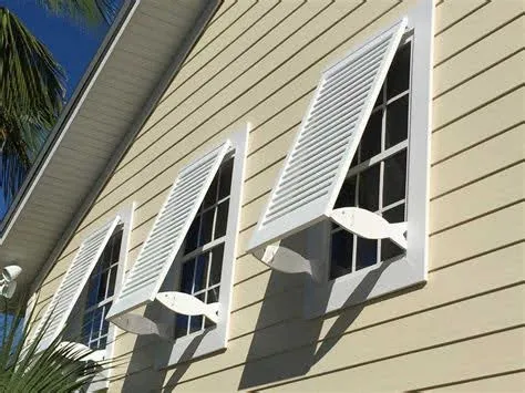 White Bahama shutters on a house with beige siding